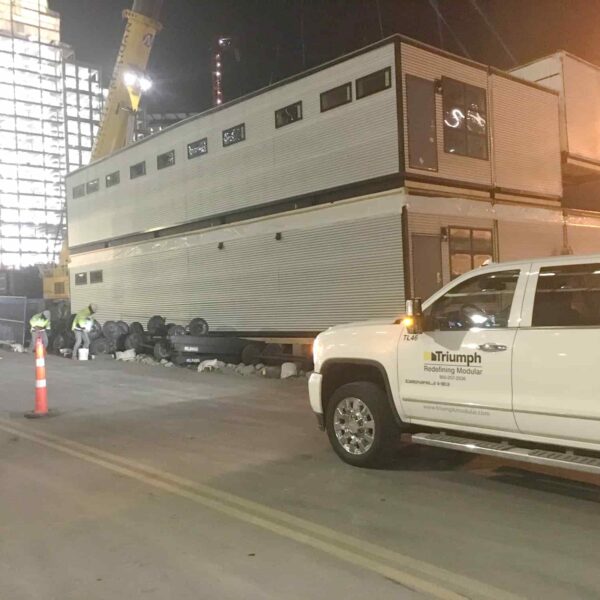 Triumph modular building being transported on-site, showcasing temporary modular construction in an urban environment.